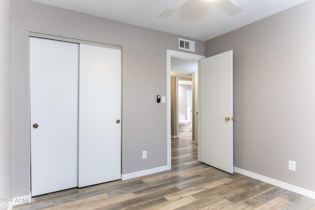 unfurnished bedroom featuring hardwood / wood-style floors, a closet, and ceiling fan