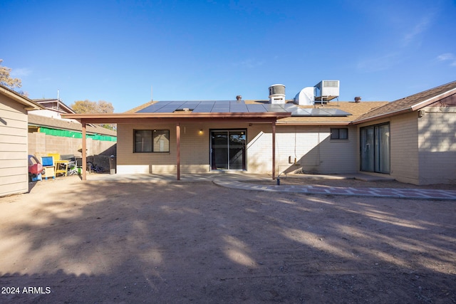 rear view of property featuring solar panels, central AC, and a patio area