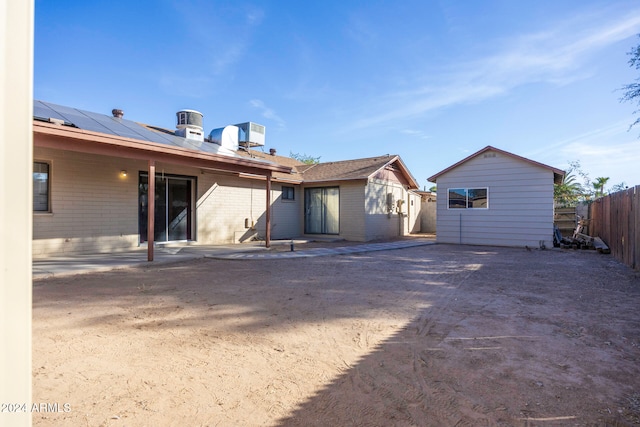 back of property featuring a storage shed, a patio area, and solar panels