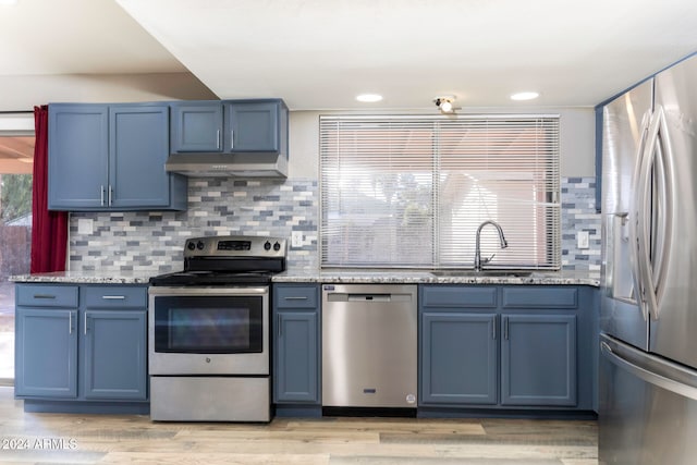 kitchen featuring blue cabinetry, sink, stainless steel appliances, and light wood-type flooring