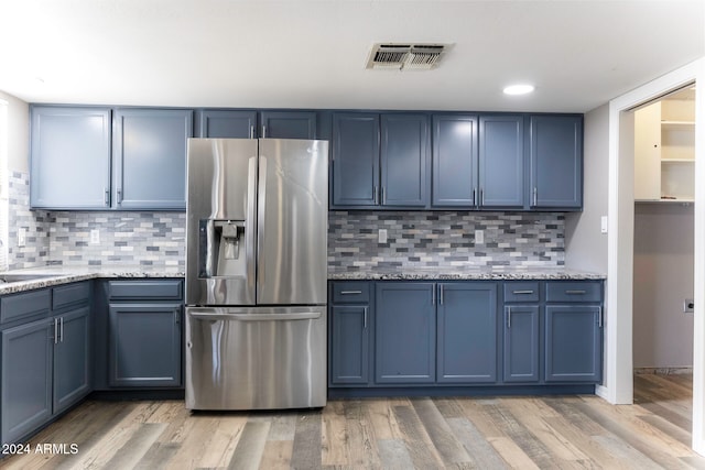 kitchen with stainless steel refrigerator with ice dispenser, tasteful backsplash, light hardwood / wood-style flooring, and blue cabinets