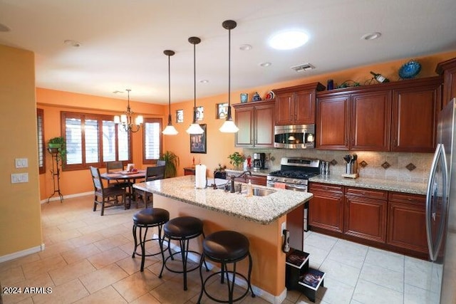 kitchen featuring pendant lighting, backsplash, a chandelier, appliances with stainless steel finishes, and sink