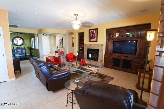 tiled living room featuring ceiling fan and a fireplace