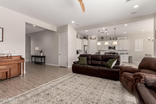 living room featuring ceiling fan and light hardwood / wood-style flooring