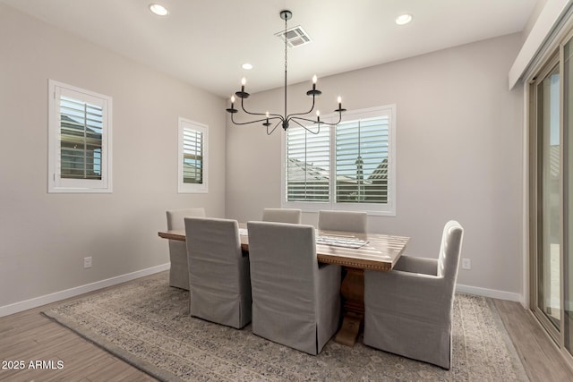 dining area with light hardwood / wood-style floors and an inviting chandelier