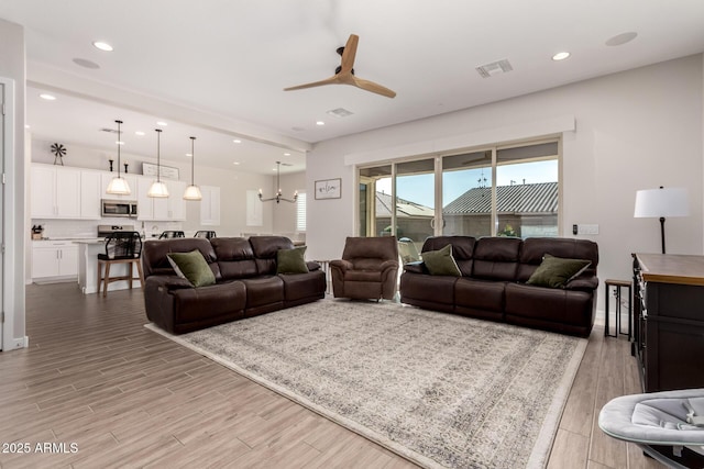 living room featuring ceiling fan with notable chandelier