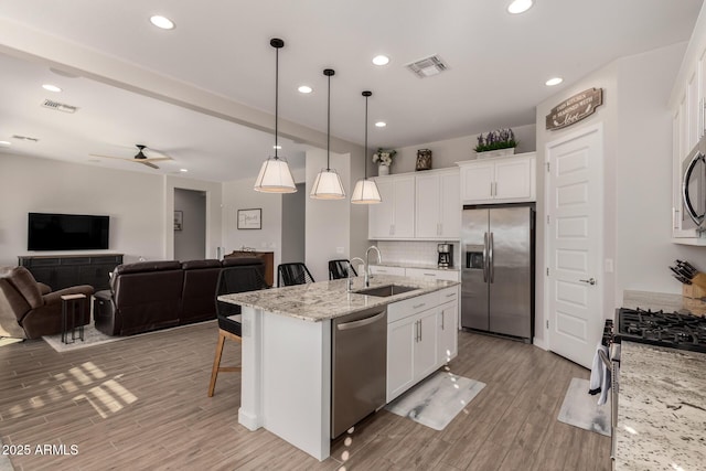 kitchen with white cabinetry, ceiling fan, a kitchen island with sink, and appliances with stainless steel finishes