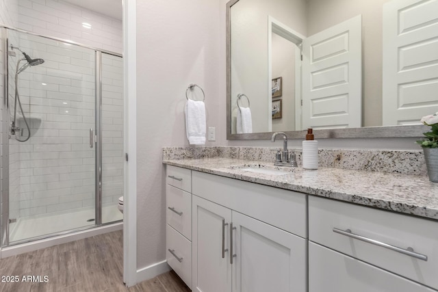 bathroom with a shower with door, toilet, vanity, and wood-type flooring