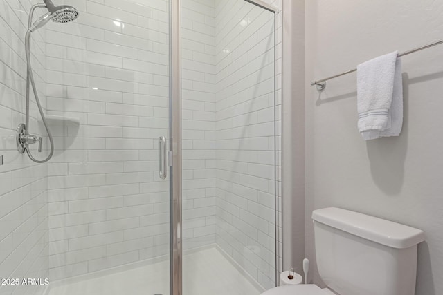 bathroom with a shower with shower door and toilet