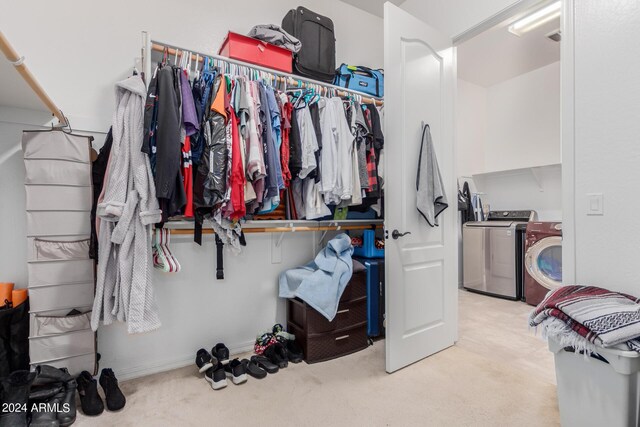 spacious closet with washer and clothes dryer and light colored carpet