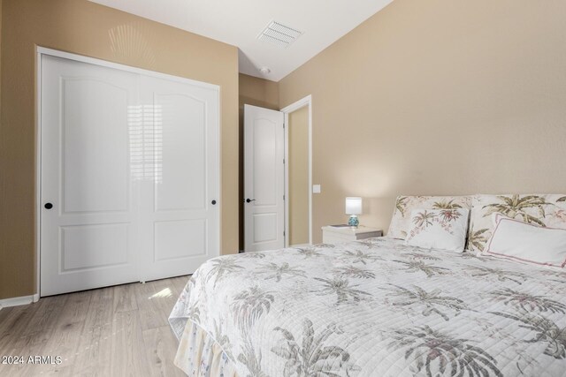 bedroom featuring light wood-type flooring, lofted ceiling, and a closet