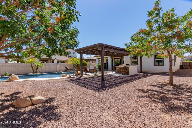 back of property with a fenced in pool, an outdoor kitchen, a pergola, and a patio area