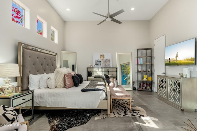 bedroom featuring ceiling fan, concrete flooring, and a high ceiling