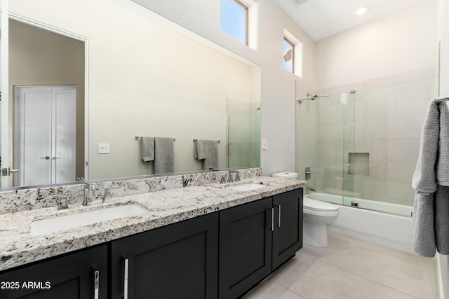 full bathroom with tile patterned flooring, vanity, bath / shower combo with glass door, and toilet