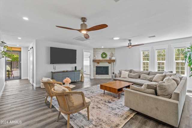 living room with ceiling fan, hardwood / wood-style flooring, and a stone fireplace