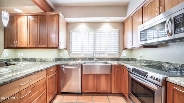 kitchen with sink, light stone counters, light tile patterned floors, and stainless steel appliances