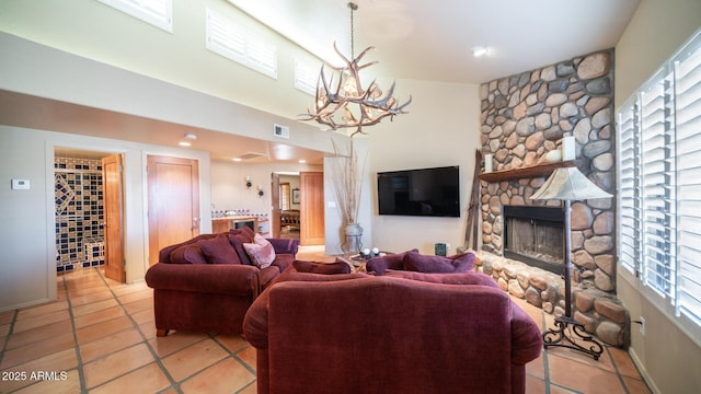 tiled living room featuring an inviting chandelier and a stone fireplace