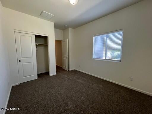 unfurnished bedroom with a closet and dark colored carpet