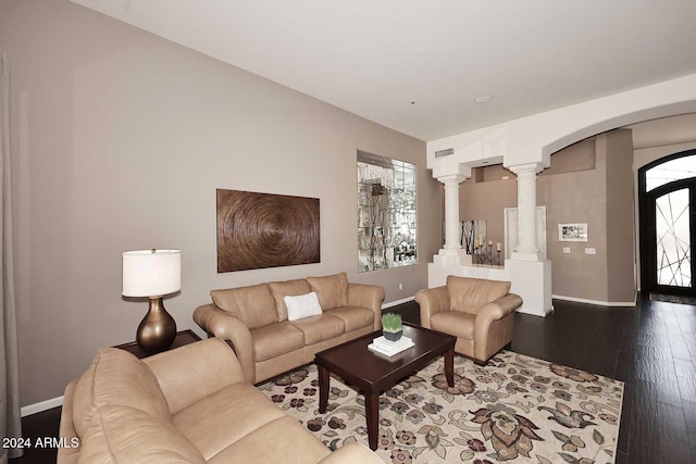 living room featuring dark wood-type flooring and decorative columns