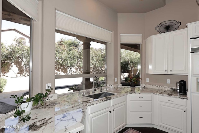 kitchen featuring white cabinets, light stone counters, and sink