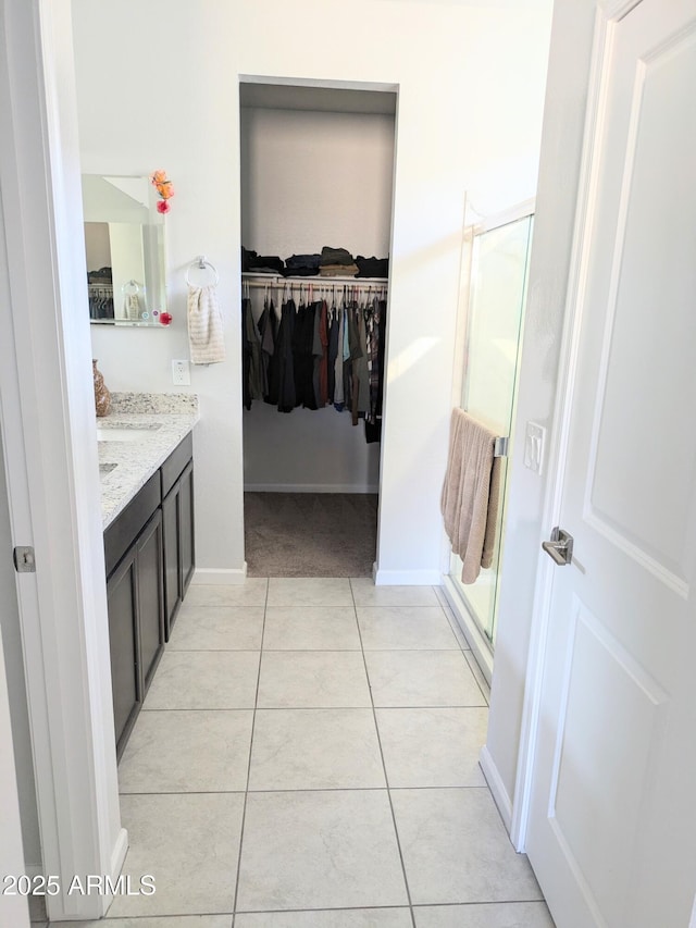 bathroom with walk in shower, vanity, and tile patterned flooring