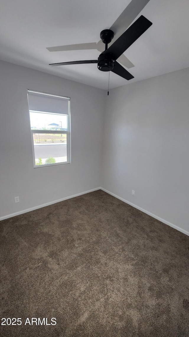 empty room featuring dark carpet and ceiling fan