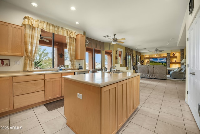 kitchen with a center island with sink, light tile patterned floors, sink, and light brown cabinetry