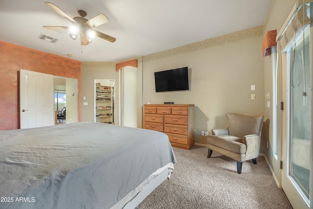 carpeted bedroom with ceiling fan, a walk in closet, and a closet