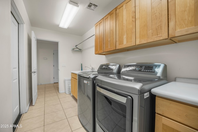 laundry room with washing machine and dryer, light tile patterned floors, and cabinets