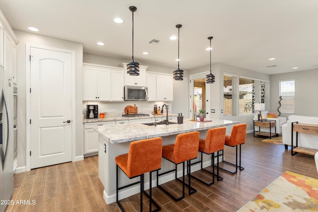 20684 W Meadowbrook Ave, Buckeye, AZ 85396 - kitchen featuring appliances with stainless steel finishes, wood finished floors, a breakfast bar area, and recessed lighting