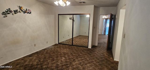 unfurnished bedroom with visible vents, carpet, a closet, a notable chandelier, and a textured ceiling