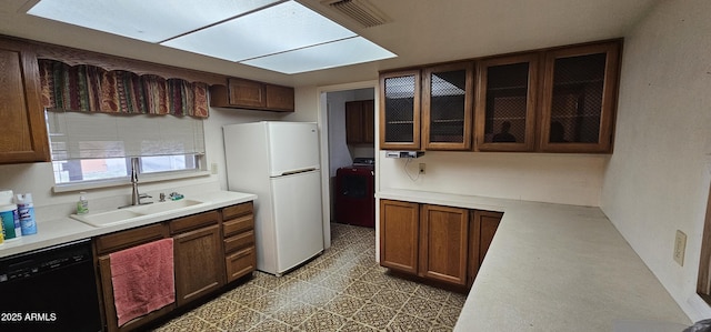 kitchen featuring washer / dryer, freestanding refrigerator, a sink, light countertops, and black dishwasher