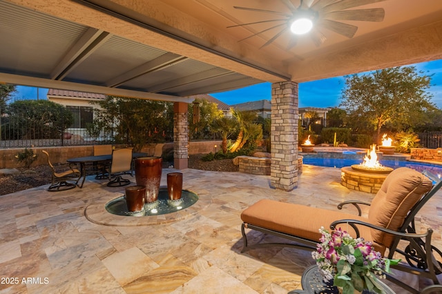 patio terrace at dusk with ceiling fan and an outdoor fire pit