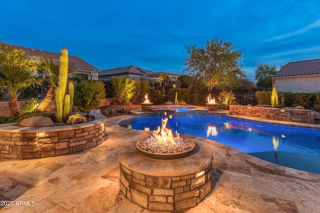 pool at dusk featuring an in ground hot tub, a patio, and an outdoor fire pit