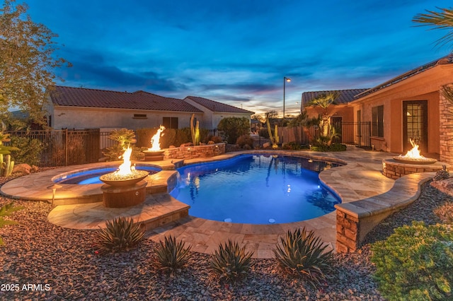 pool at dusk with an outdoor fire pit and a patio