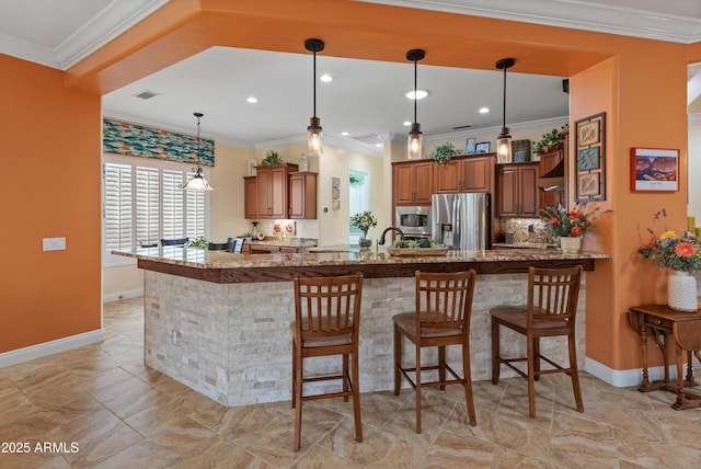 kitchen featuring appliances with stainless steel finishes, pendant lighting, a kitchen bar, and kitchen peninsula