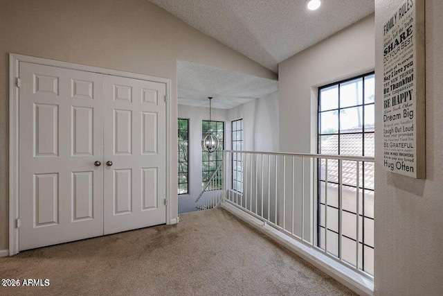 interior space with vaulted ceiling, a chandelier, carpet flooring, and a textured ceiling