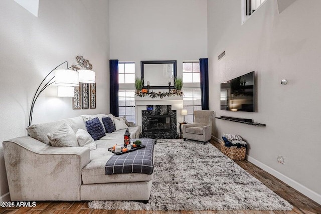 living room with a premium fireplace, a high ceiling, and dark hardwood / wood-style floors