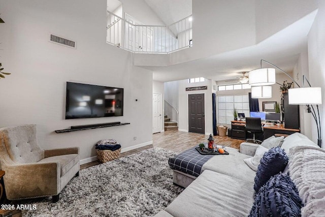 living room featuring ceiling fan, wood-type flooring, and a towering ceiling