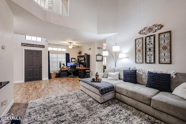 living room featuring ceiling fan, a high ceiling, and hardwood / wood-style floors