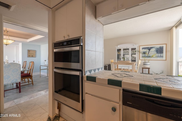 kitchen featuring tile countertops, light tile patterned flooring, white cabinets, and appliances with stainless steel finishes