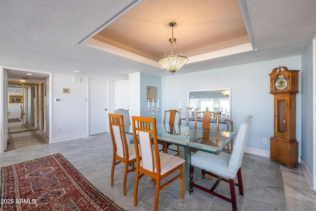 dining area featuring a raised ceiling and a textured ceiling