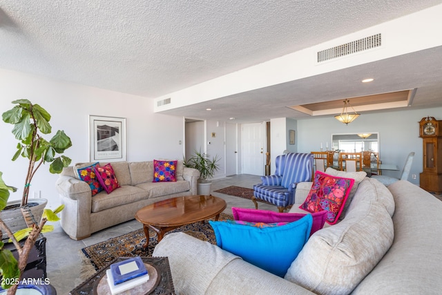 living room featuring a raised ceiling and a textured ceiling