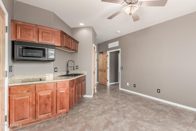 5347 E 10th Ave, Apache Junction, AZ 85119 - kitchen with black microwave, brown cabinets, light stone counters, ceiling fan, and recessed lighting