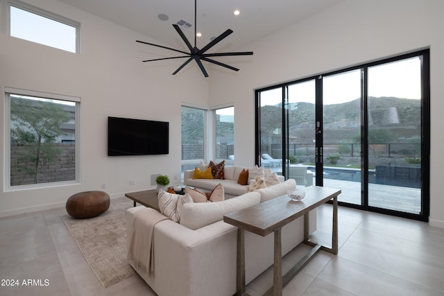 living room with light tile patterned flooring, a wealth of natural light, ceiling fan, and high vaulted ceiling