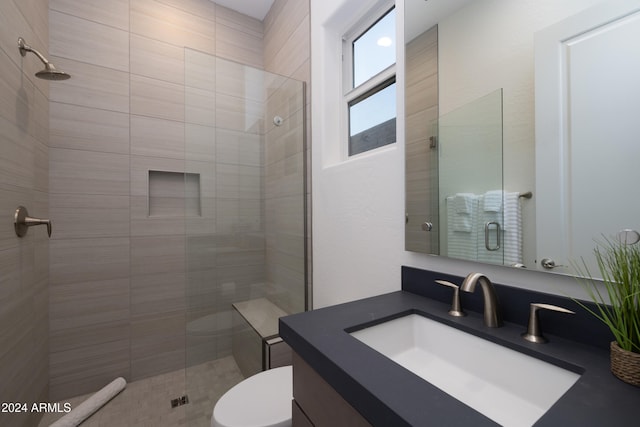 bathroom featuring toilet, vanity, and a shower with shower door