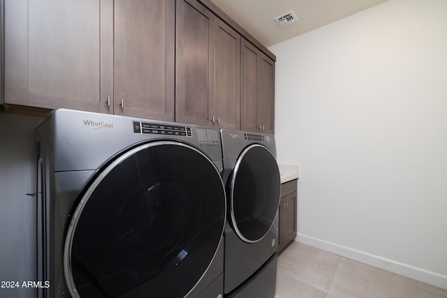 washroom featuring light tile patterned flooring, cabinets, and washing machine and clothes dryer