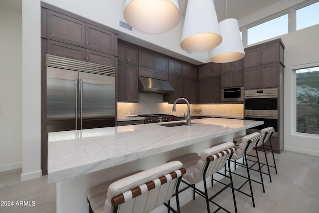 kitchen featuring stainless steel appliances, a kitchen bar, sink, and decorative light fixtures