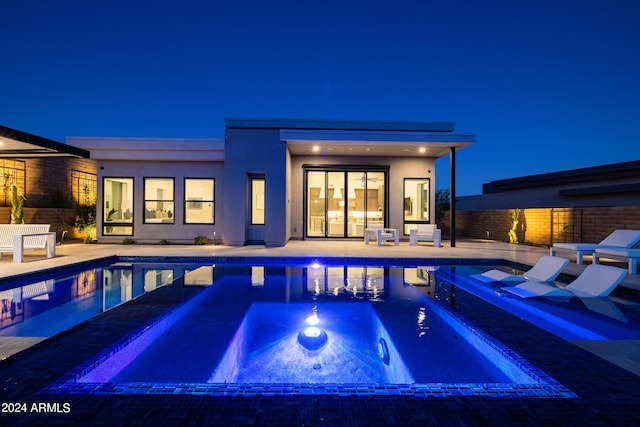 pool at twilight featuring a patio area and an in ground hot tub