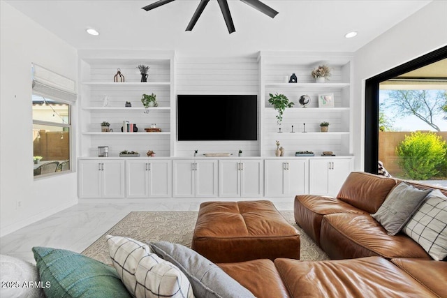 living room featuring ceiling fan, built in shelves, and plenty of natural light